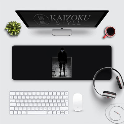 A minimalist desk mat featuring Sung Jinwoo from Solo Leveling, standing in a shadowy, ominous pose. The black background emphasizes a central framed image of him with glowing blue eyes, set on a stone-tiled floor. The design exudes a dark and commanding presence, perfect for fans of the series.